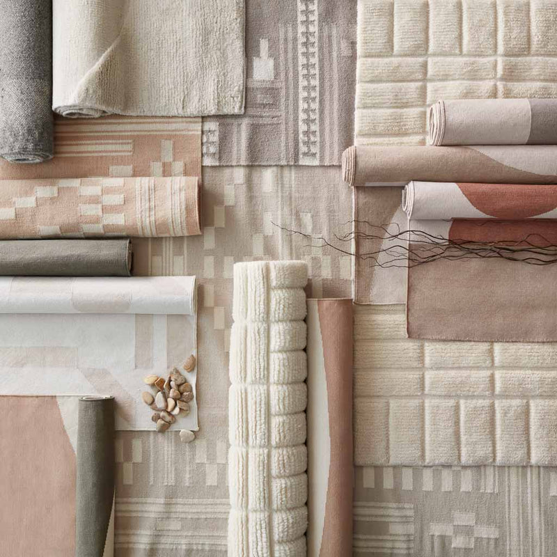Overhead shot of woven and flatweave rugs in neutral tones layered, flax