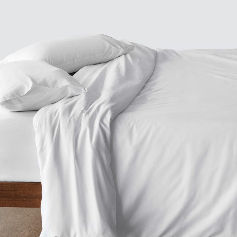 Side of bed with duvet and pillows, white