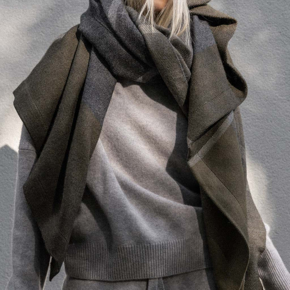 Model wrapped in olive, charcoal, and indigo alpaca throw