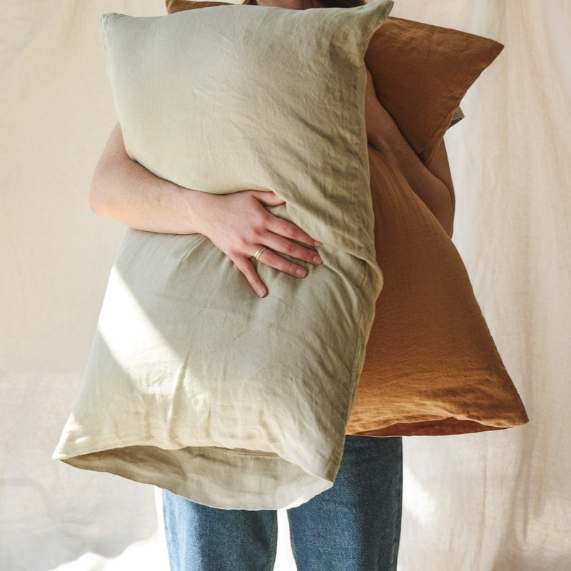 Someone holding sage green and camel pillow, sage