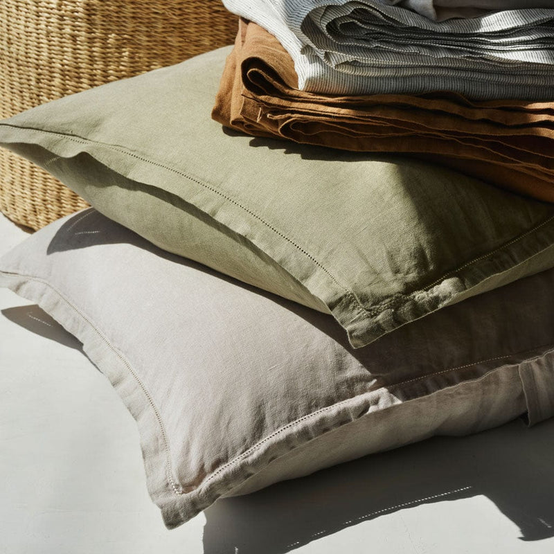 Stack of linen pillowcases on two pillows, solid-sand
