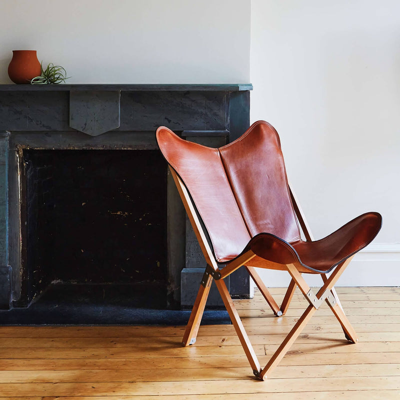 Leather sling chair in front of fireplace, cognac