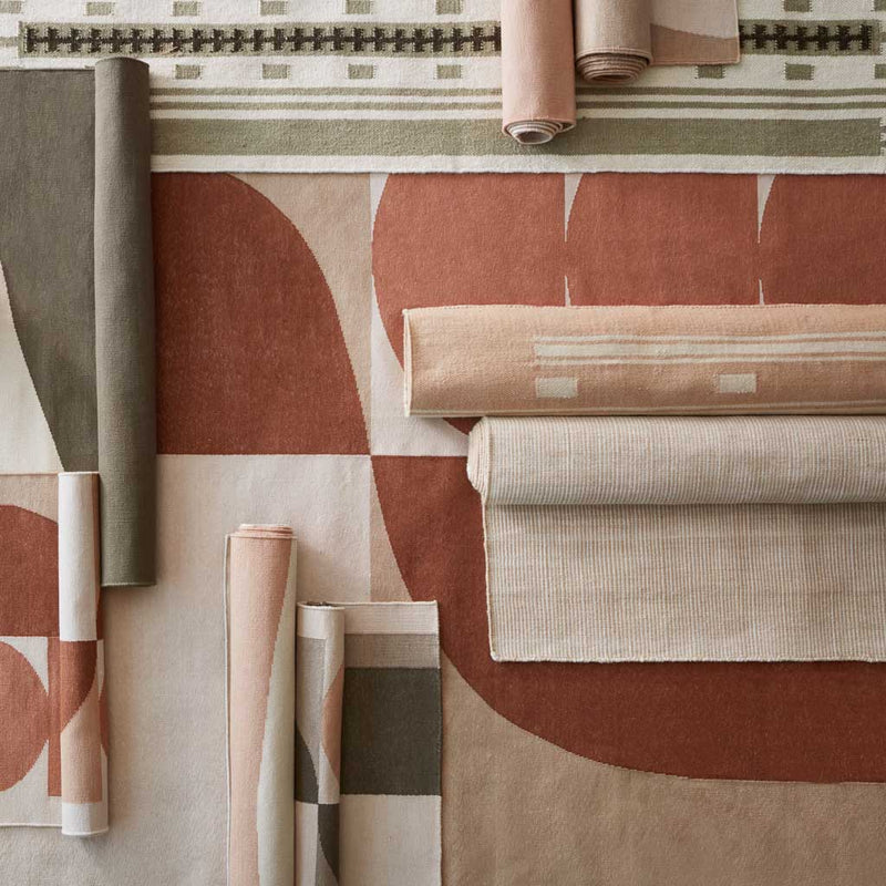Overhead of flatweave rugs in olive and rust hues layered, rose