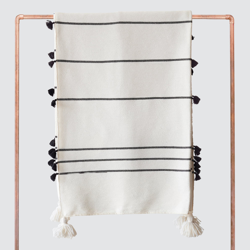 Striped Moroccan tassel blanket hanging over copper rack