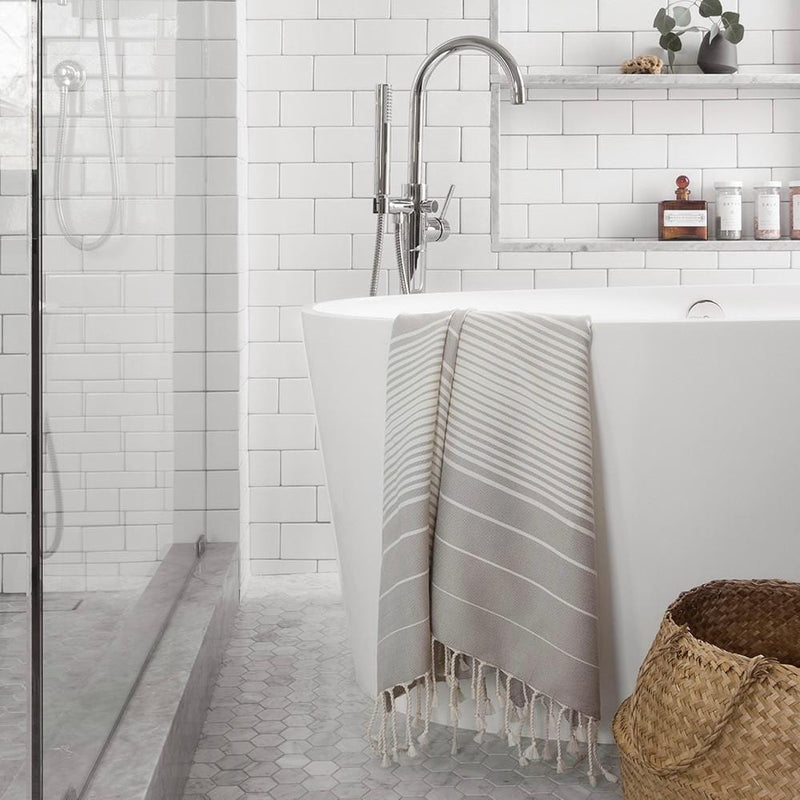 Striped towel hanging over bathtub, stone-grey
