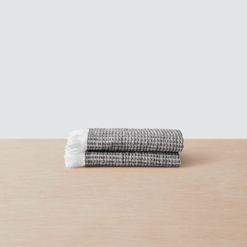 Stack of two black face towels with white fringe, black