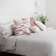 Geometric pillow styled with throws on bed, cream and blue and peach