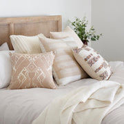 Geometric pillow styled on bed, cream and blue and peach