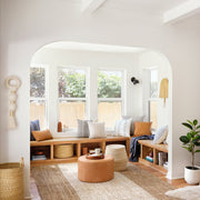 Handwoven Basket in Natural Materials styled in room with leather ottoman, natural