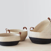 Stack of black and natural woven storage baskets with leather handles, black