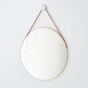 Large circular mirror hanging from leather strap, untinted