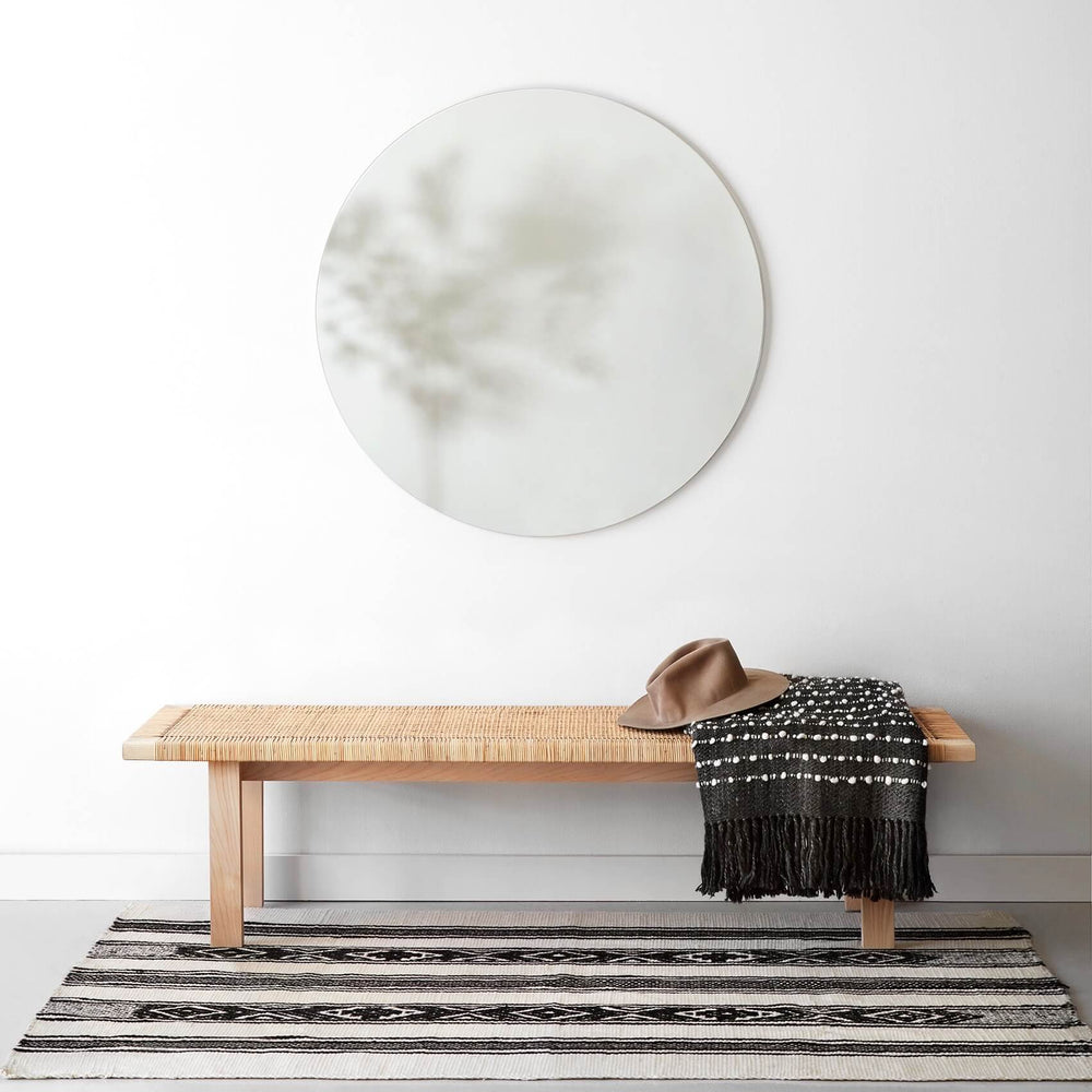 Large circular mirror above bench with throw