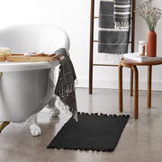Black bath mat with bathtub and wood bath furniture, black