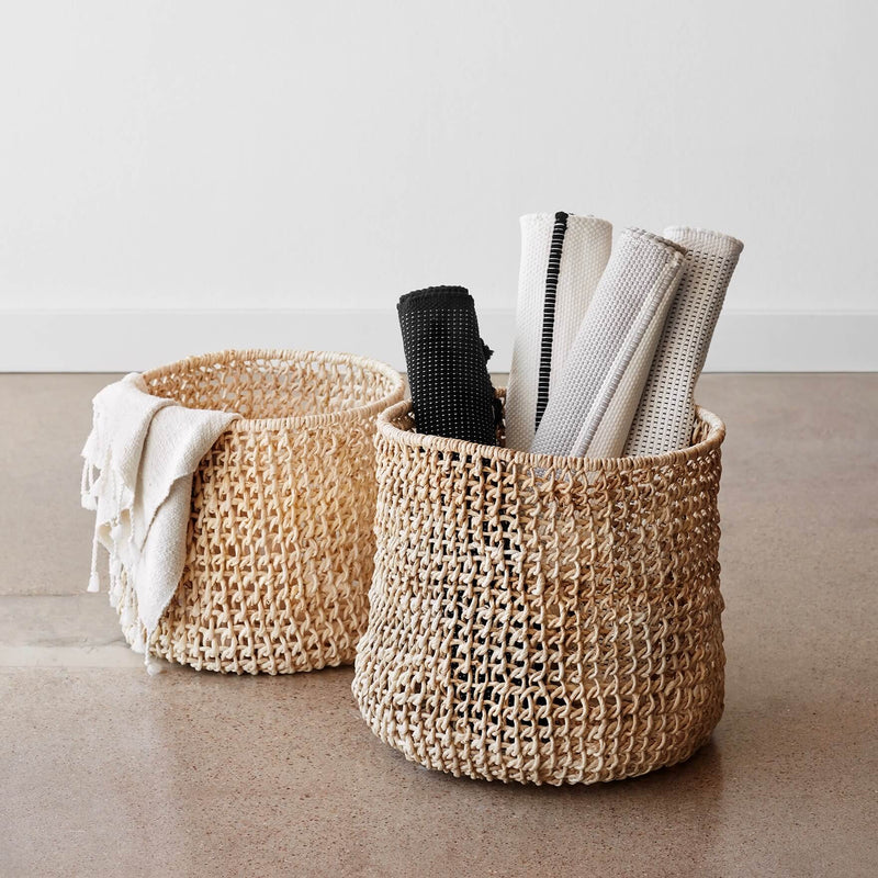 Rolled up bath mats sitting in basket, ivory