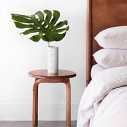 teak wooden side table by bed with ceramic vase