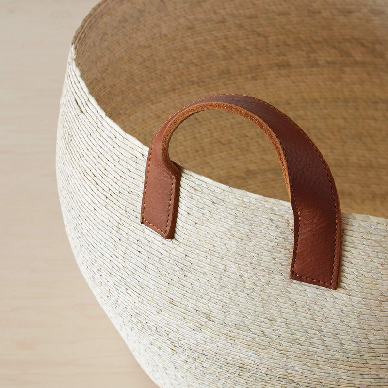 Detailed stitching on leather handles of palm basket, natural