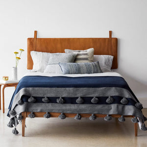 Hanging leather headboard behind styled bed,caramel