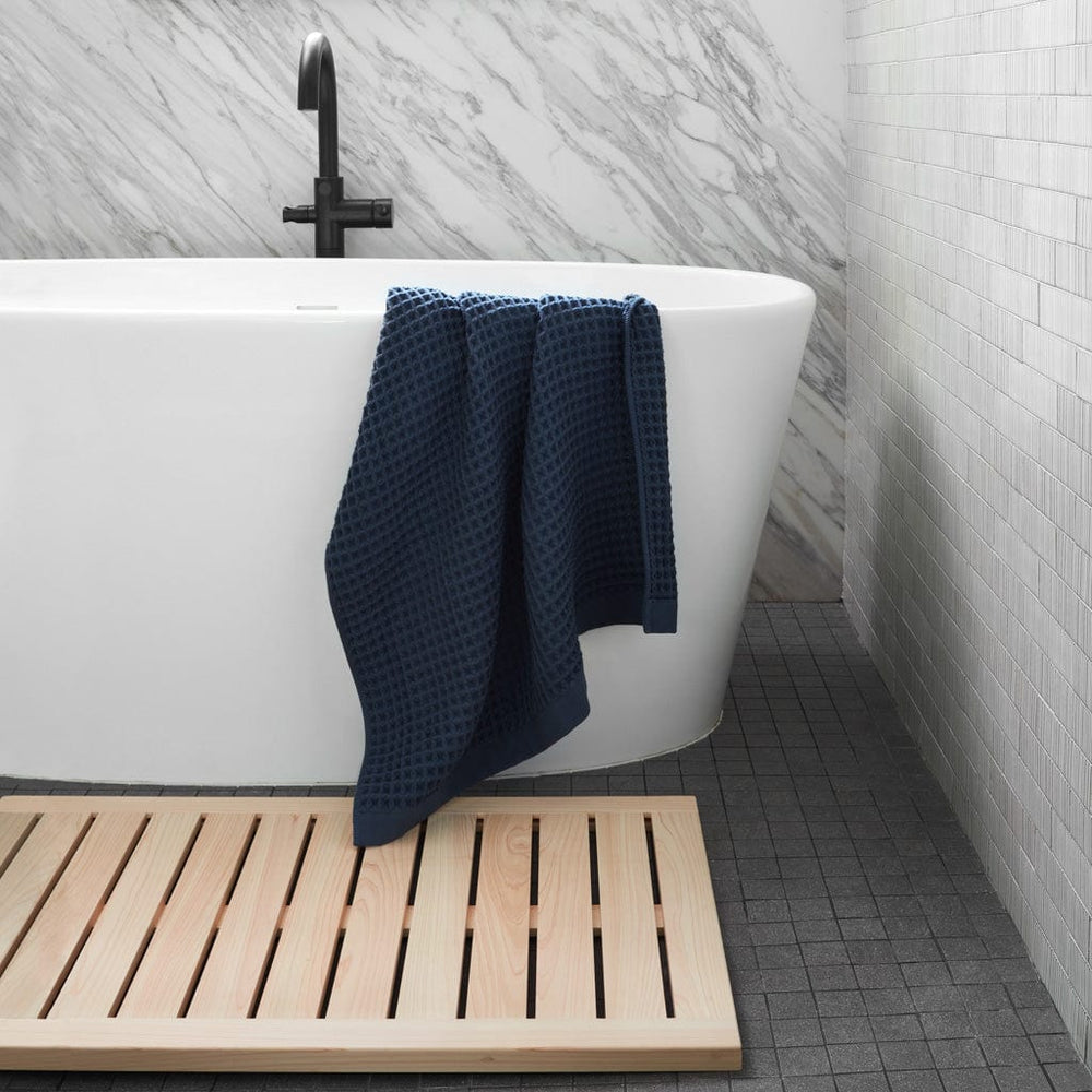 Hinoki Wood Bath Mat and Navy Waffle Towel in Marble Bathroom