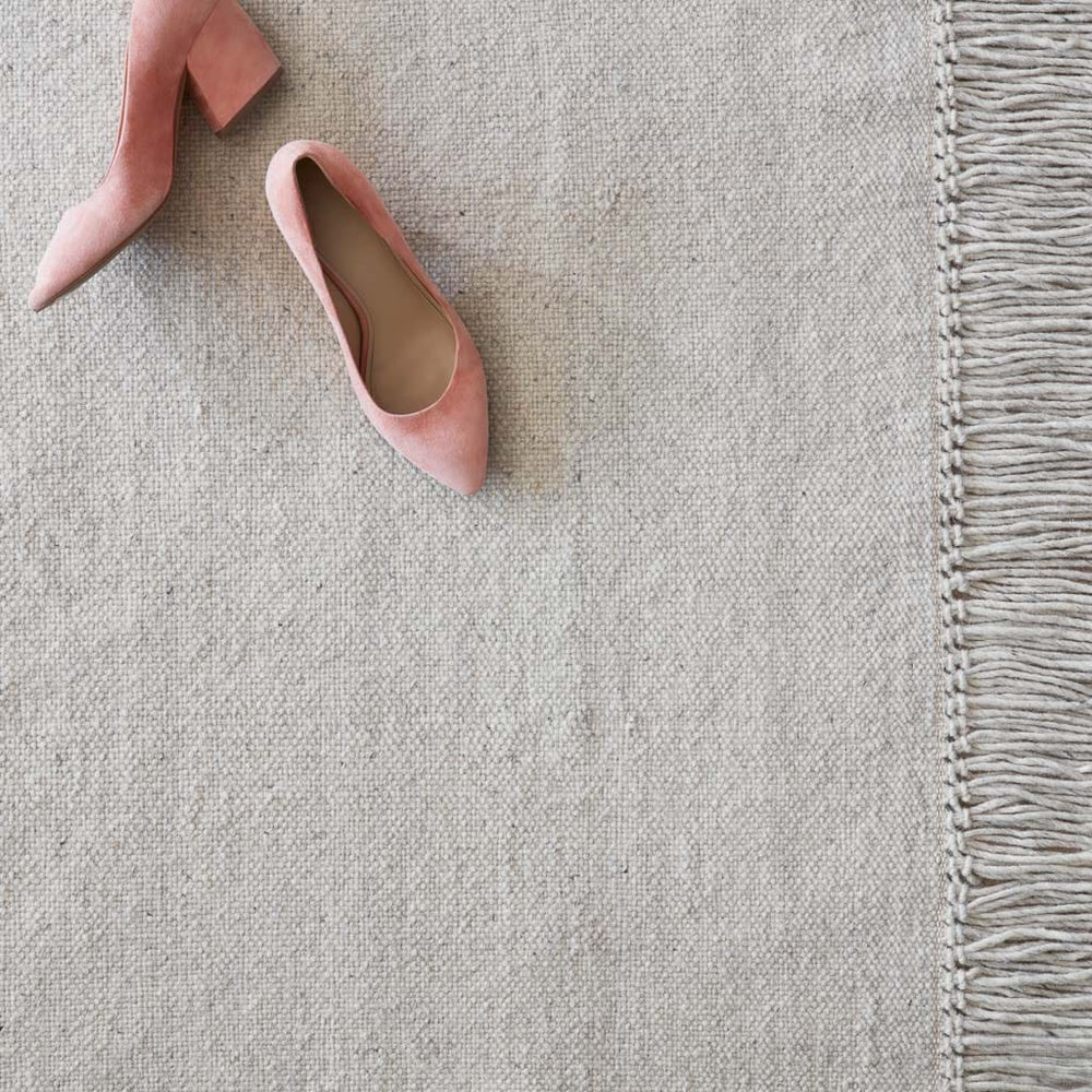 Weave and Fringe Detail on Soft Grey Rug with Pink Shoes