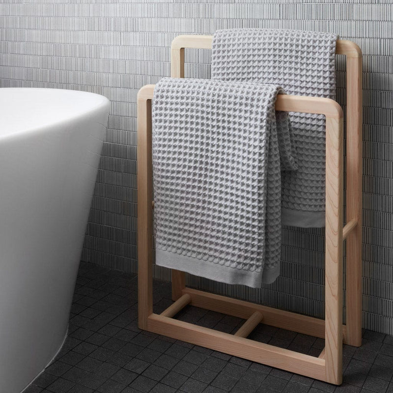 Waffle bath towels over wood towel rack, light-grey