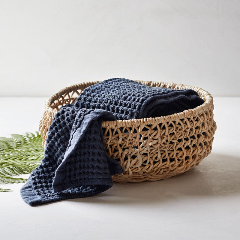 Folded waffle towels in small woven basket, indigo