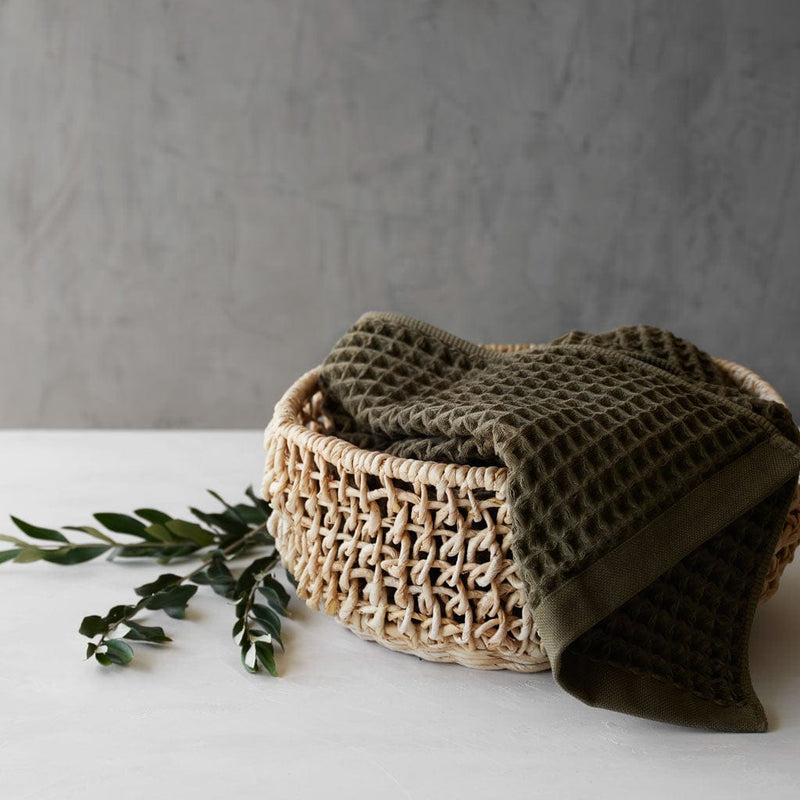 Waffle towel inside of small woven basket, olive