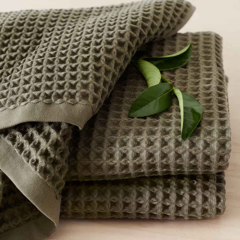 Folded olive green waffle towels with greenery, olive