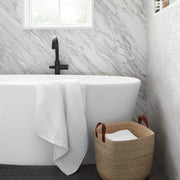 Waffle towel draped over bath tub, white