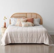 Light rattan headboard behind styled bed