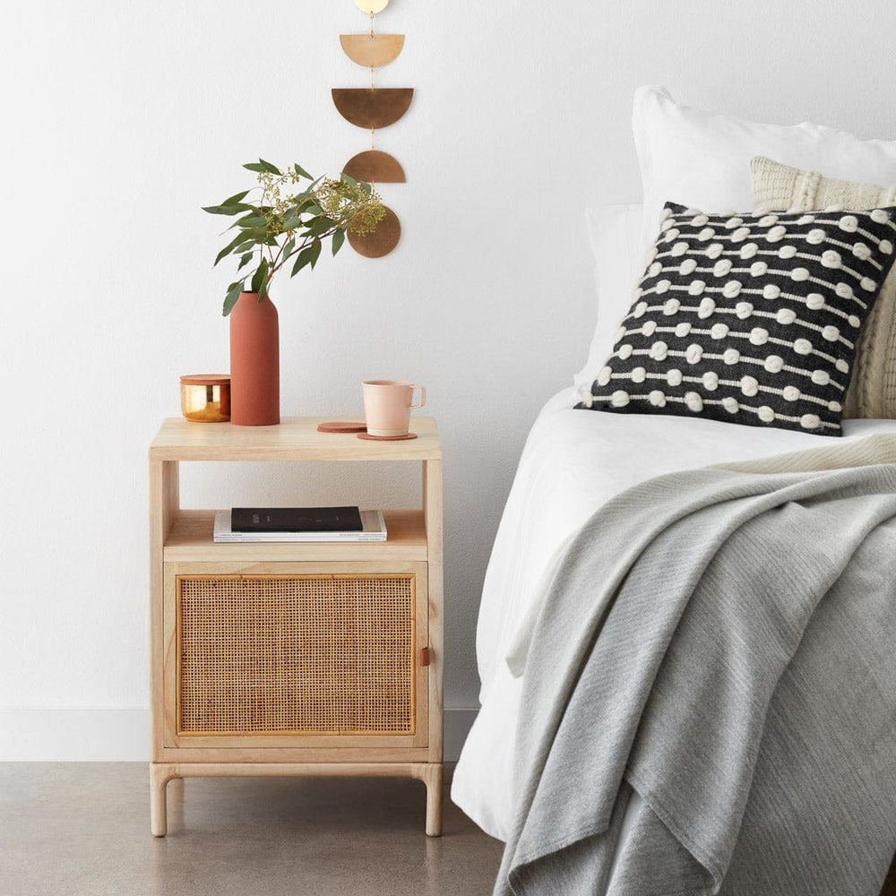 Cane and wood nightstand next to bed, light-mindi
