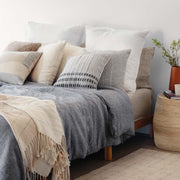 Wool pillow and alpaca throw styled on bed, stone