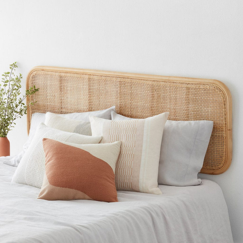 Light cane headboard behind styled pillows