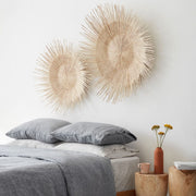 Handwoven Palm Wall Hangings above Linen Bedding on Bed