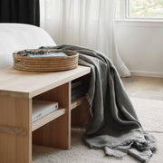 Woven palm tray on wood bench with throw