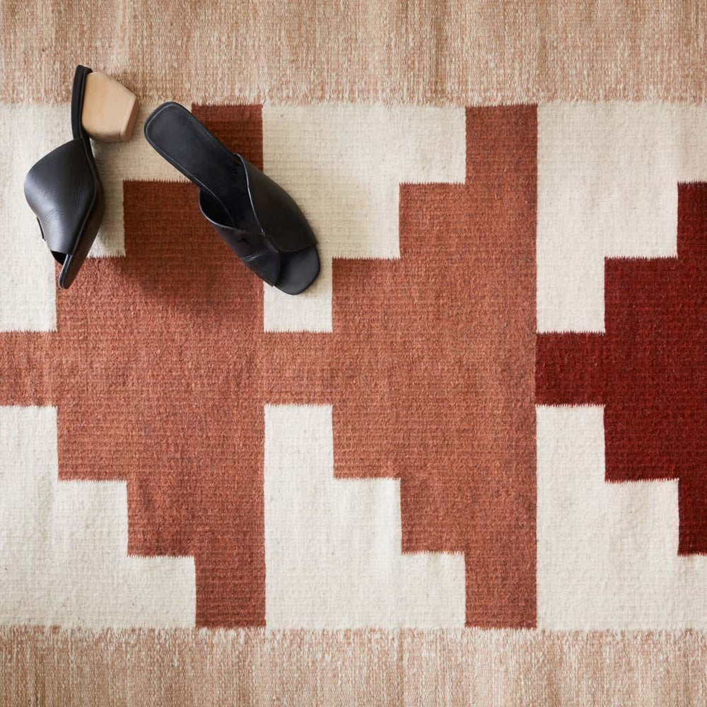 Handwoven Wool Accent Rug in Rust and Cream Styled with Shoes
