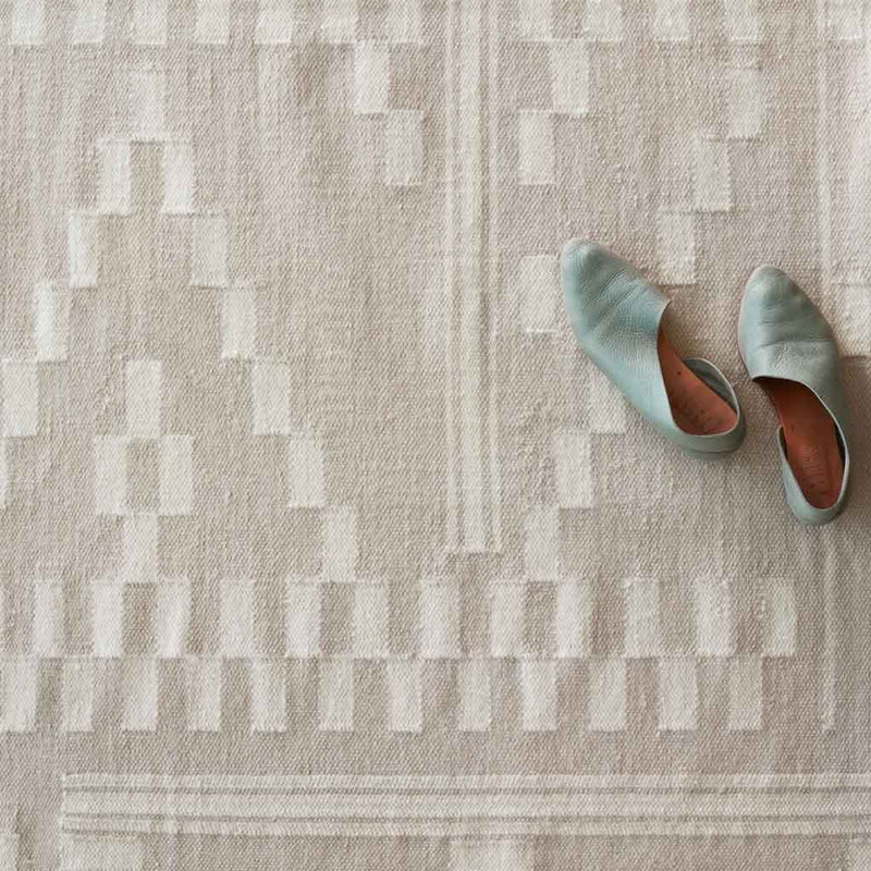 Detailed closeup of woven rug weave styled with shoes, flax