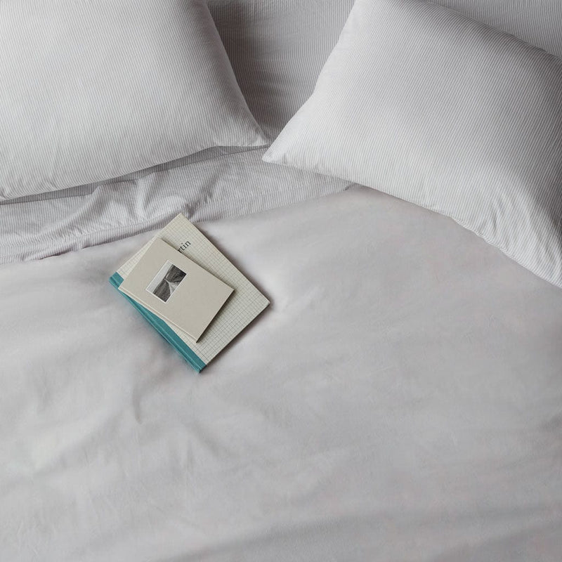 Book lying on top of duvet cover, solid-light-grey