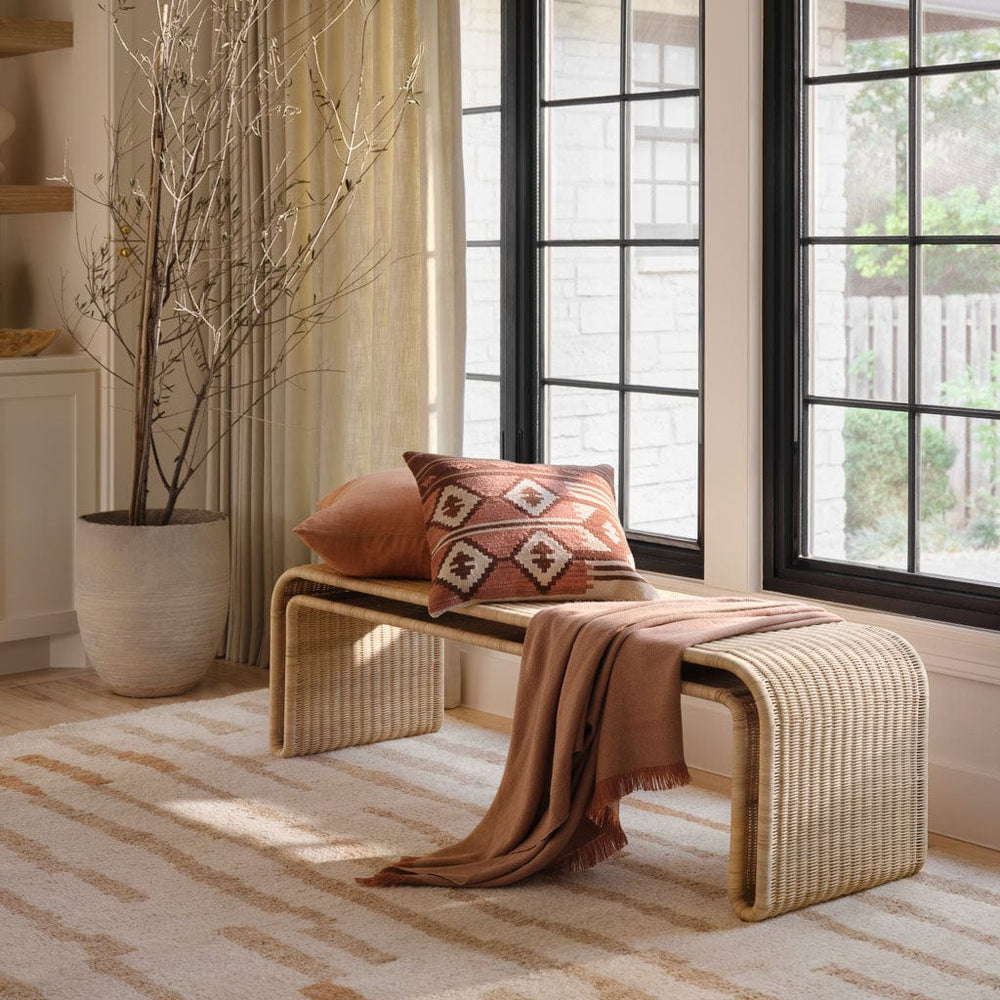 Penida modern wicker bench with kilim pillows in front of windows