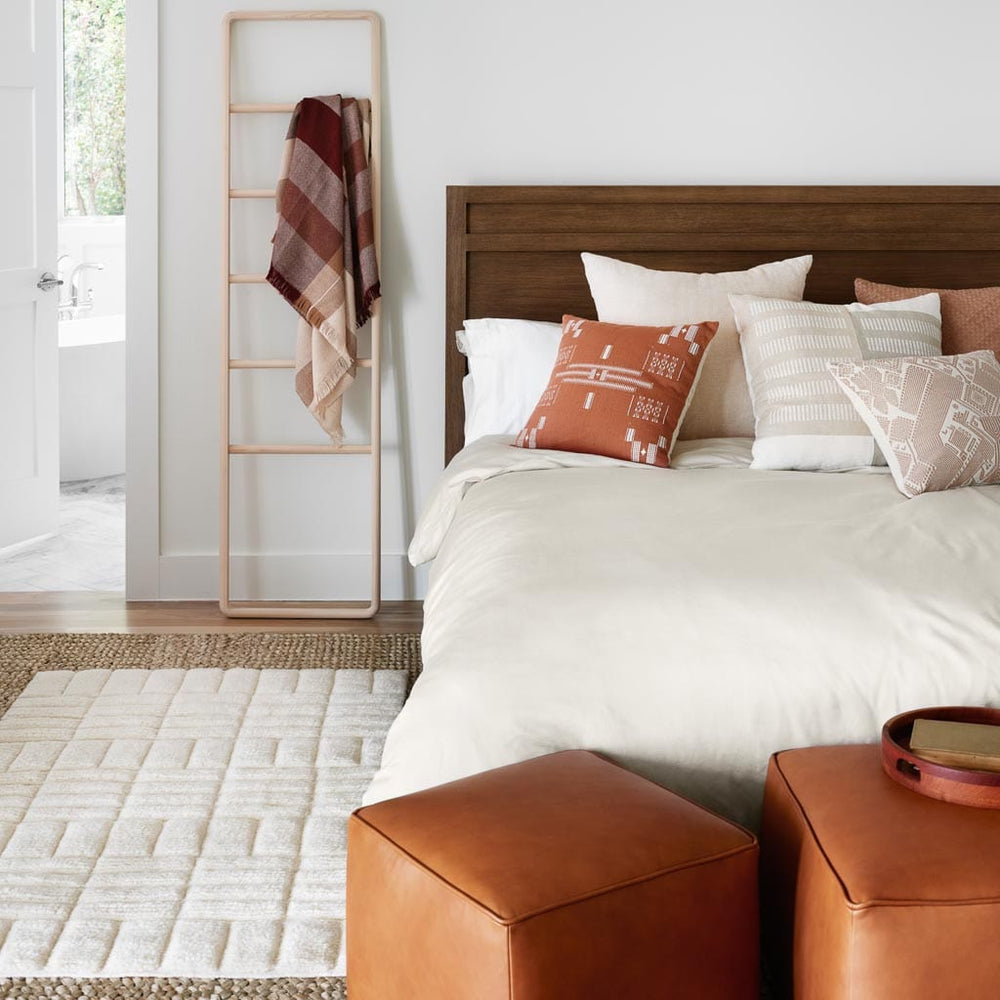 Textured Wool Rug styled next to modern bed and tan leather ottomans
