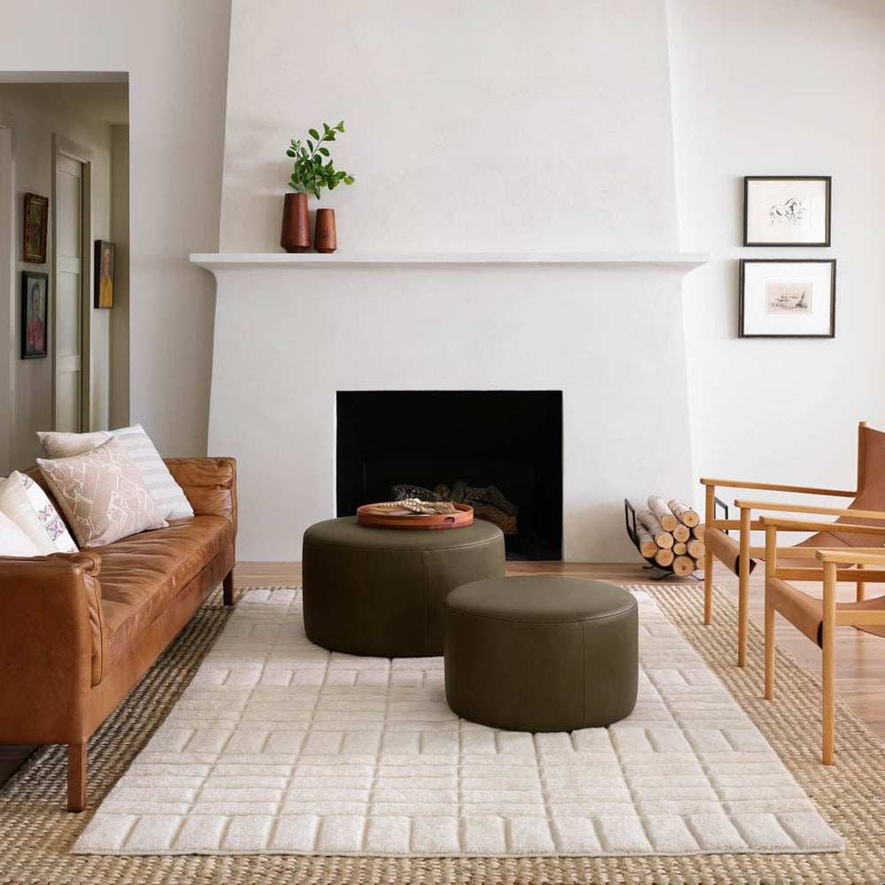 Modern living room. Olive leather ottomans sit on cream textured wool area rug