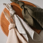 Linen napkins styled overhead with wood serving board, rose