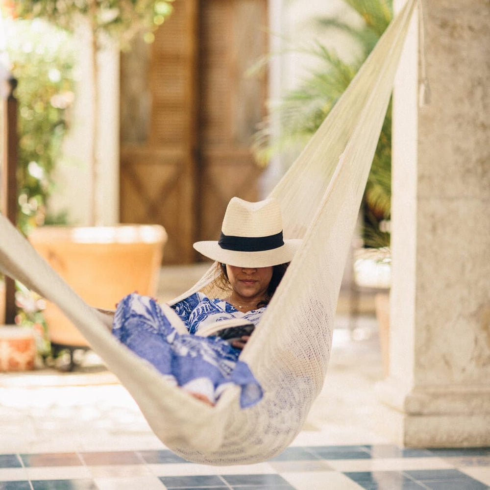 Person wearing fedora hat lounging in hammock