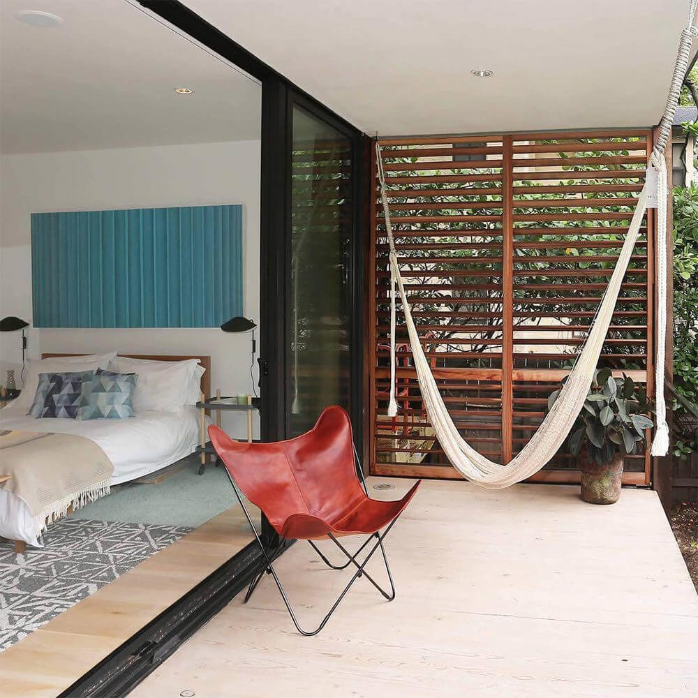 Hammock hanging on outdoor balcony. Leather chair sitting beside.