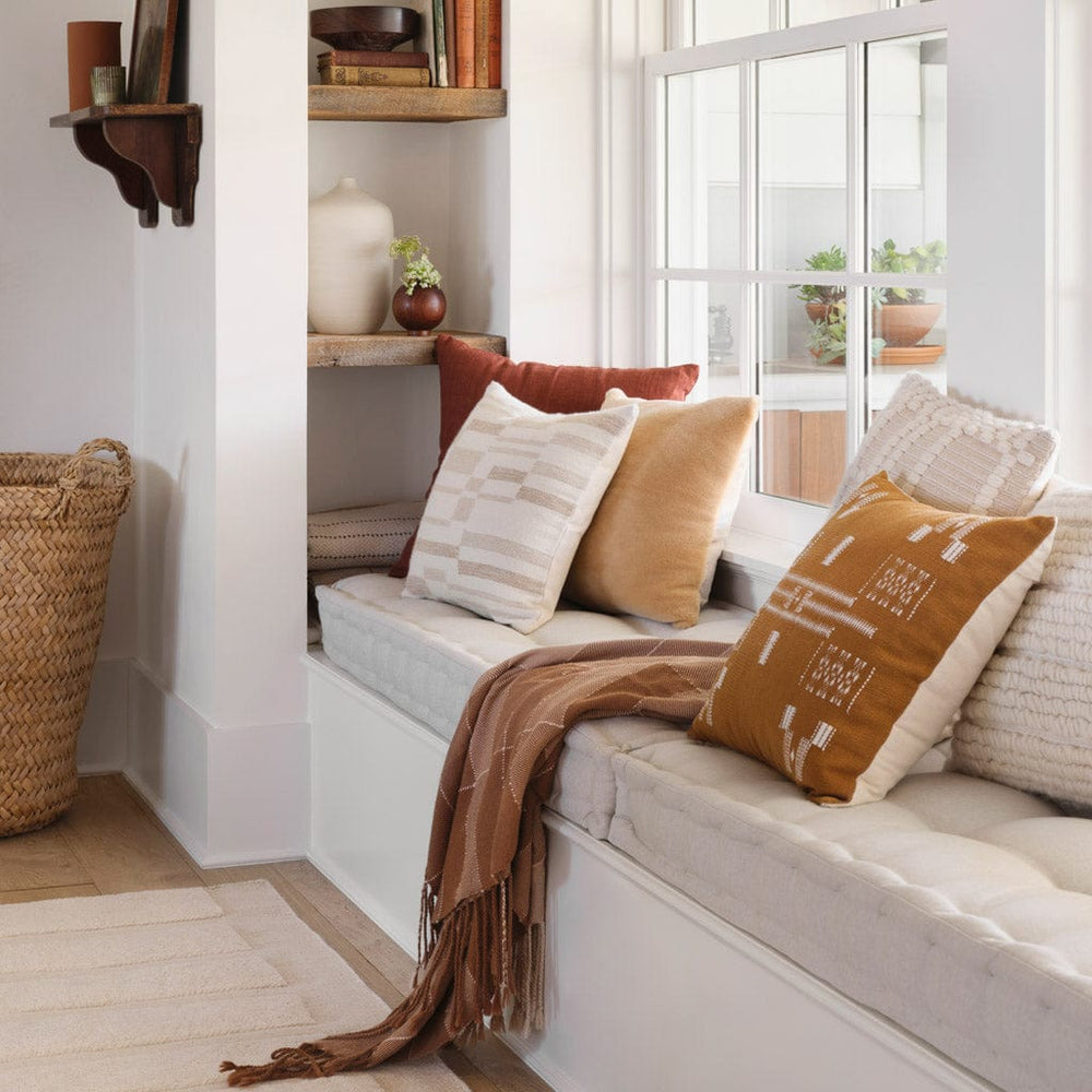 Window seat styled with throw pillows in shades of rust and tan