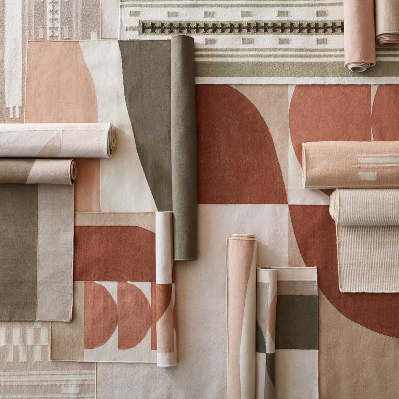 Overhead of flatweave rugs in olive and rust hues layered, flax