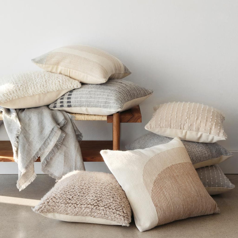 boucle pillow styled on bench with other pillows, sand