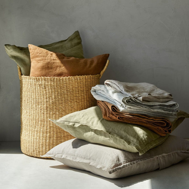 Linen pillows and pillowcases stacked, solid-sand