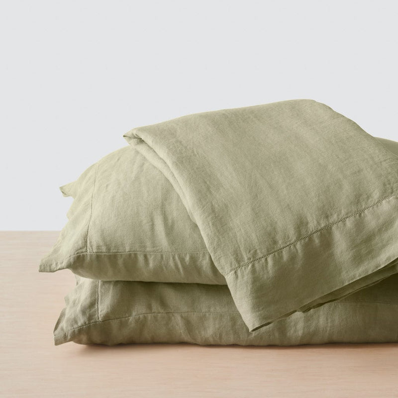 Top sheet folded on stack of two sage green pillows, sage