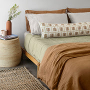 Block print lumbar on sage green quilt and camel sheet set, solid-sand