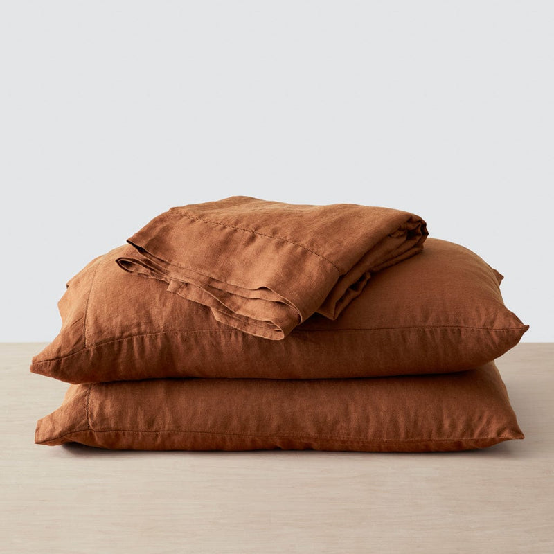 Top sheet folded on stack of two linen pillows, sienna
